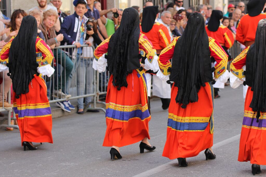 Donne di Desulo in sfilata con il costume tradizionale rosso e giallo e il velo nero