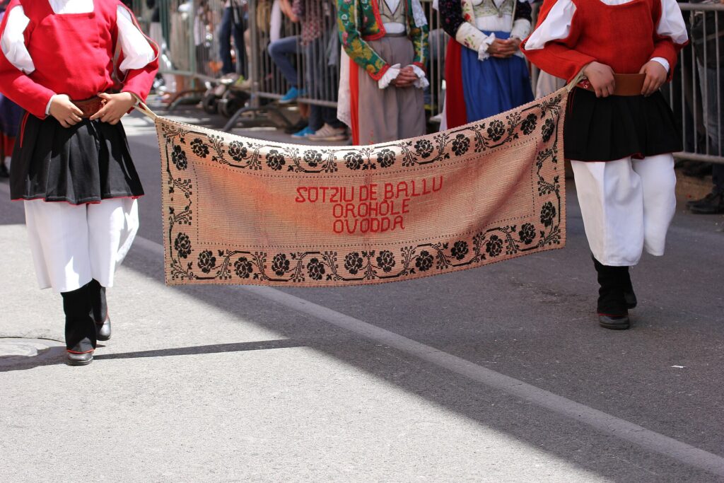 Gruppo folk di Ovodda in costume tradizionale con lo stendardo del paese